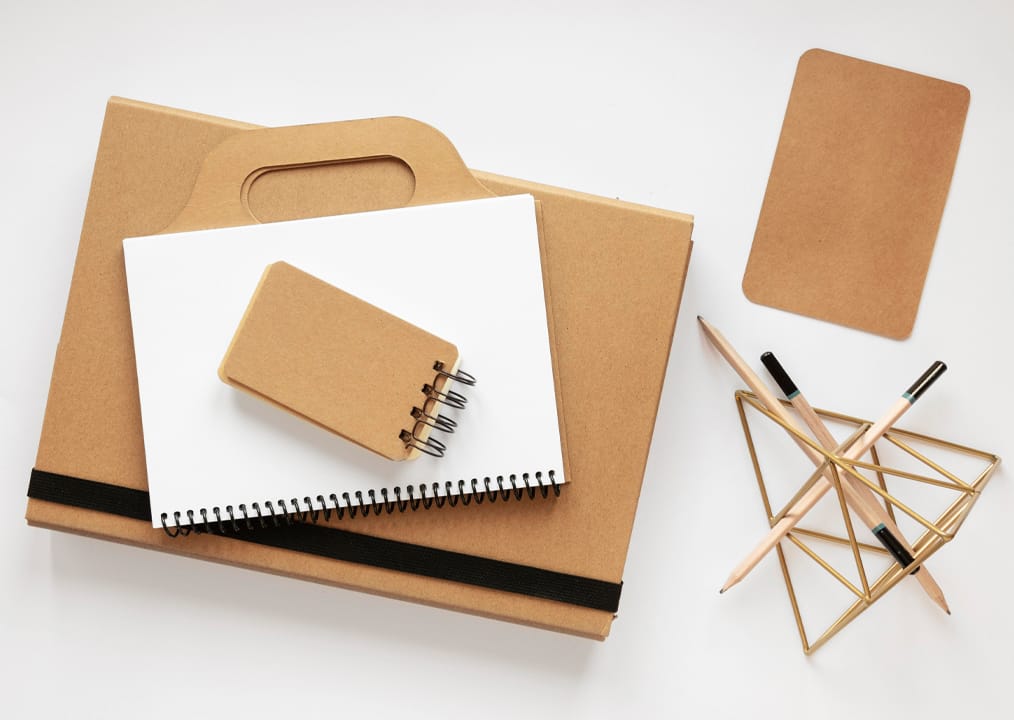 Eco stationery set – kraft notebook, gift bag and pencils Kraft notebook, gift bag and pencils arranged on a white desk