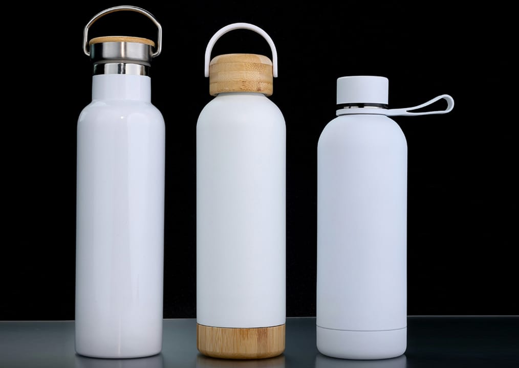 Insulated bottles with bamboo lids – set of three Three white insulated bottles with bamboo lids on a black background